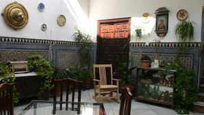 A room with a tiled floor, a wooden chair, a glass table, and a door. - Pensión El Portillo (Córdoba)
