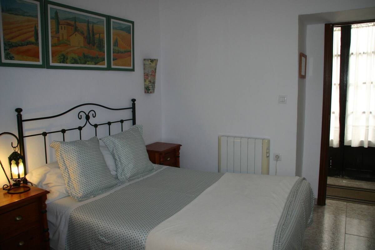 A bedroom with a bed, nightstand, lamp, and wall art.