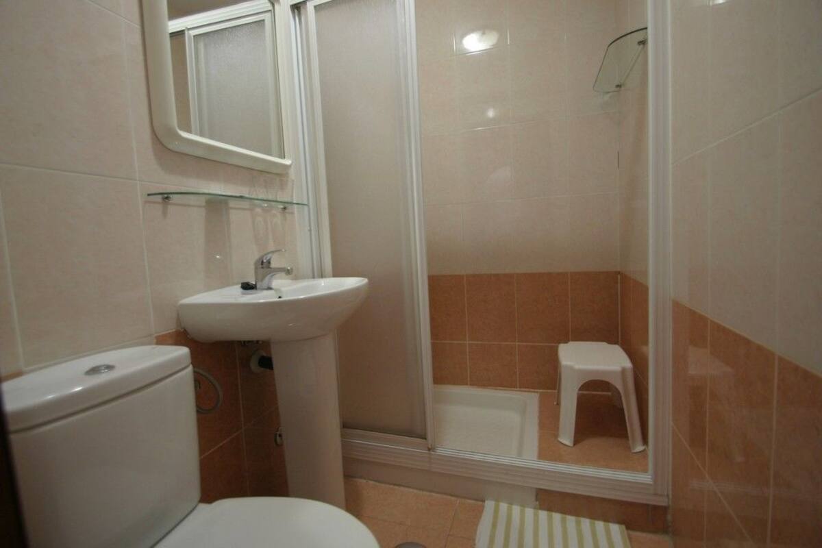 A bathroom with a toilet, sink, and shower area.