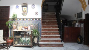 A staircase with a tiled wall, a wooden door, and a potted plant. - Pensión El Portillo (Córdoba)