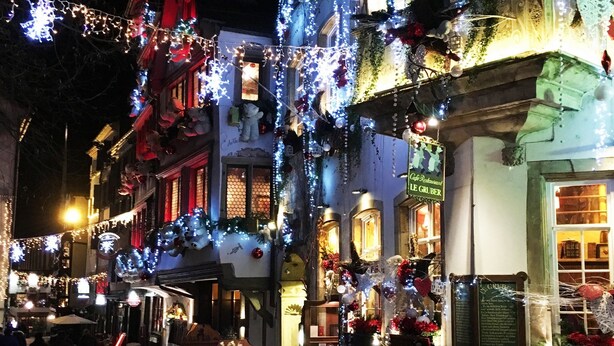 A cobblestone street lined with buildings decorated with festive lights and ornaments. - Adonis Hotel Strasbourg (Strasbourg)