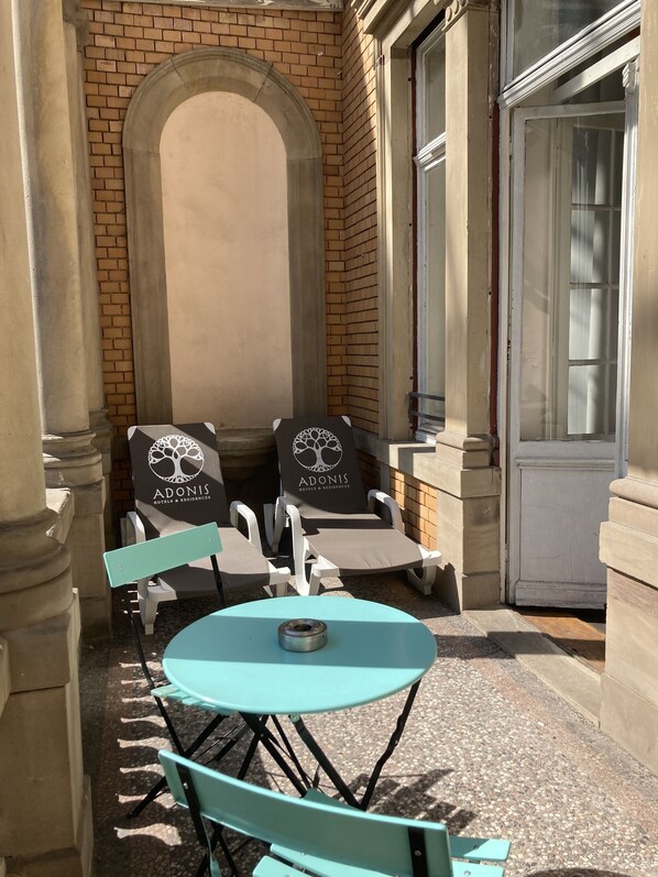 An outdoor seating area with two lounge chairs and a table, a brick wall, and a door.