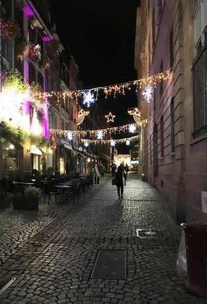 A cobblestone street lined with buildings, decorated with string lights and star-shaped ornaments. - Adonis Hotel Strasbourg (Strasbourg)