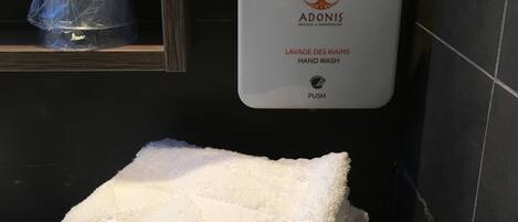 A hand wash station with a towel dispenser in a hotel bathroom.