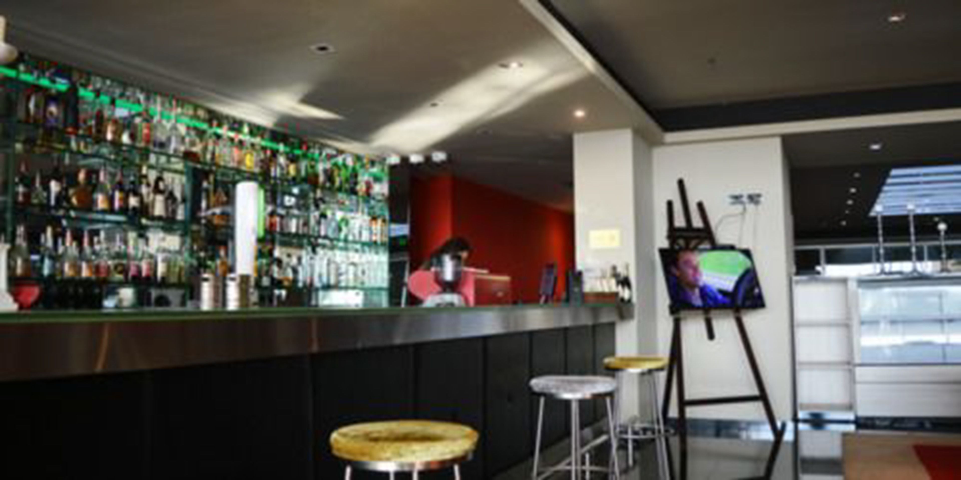 Zona de bar con varios botellones, taburetes y una pantalla de televisión.