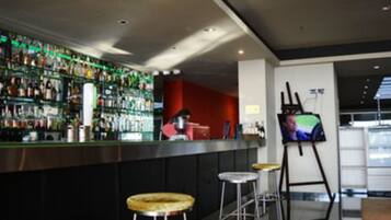 Zona de bar con varios botellones, taburetes y una pantalla de televisión.