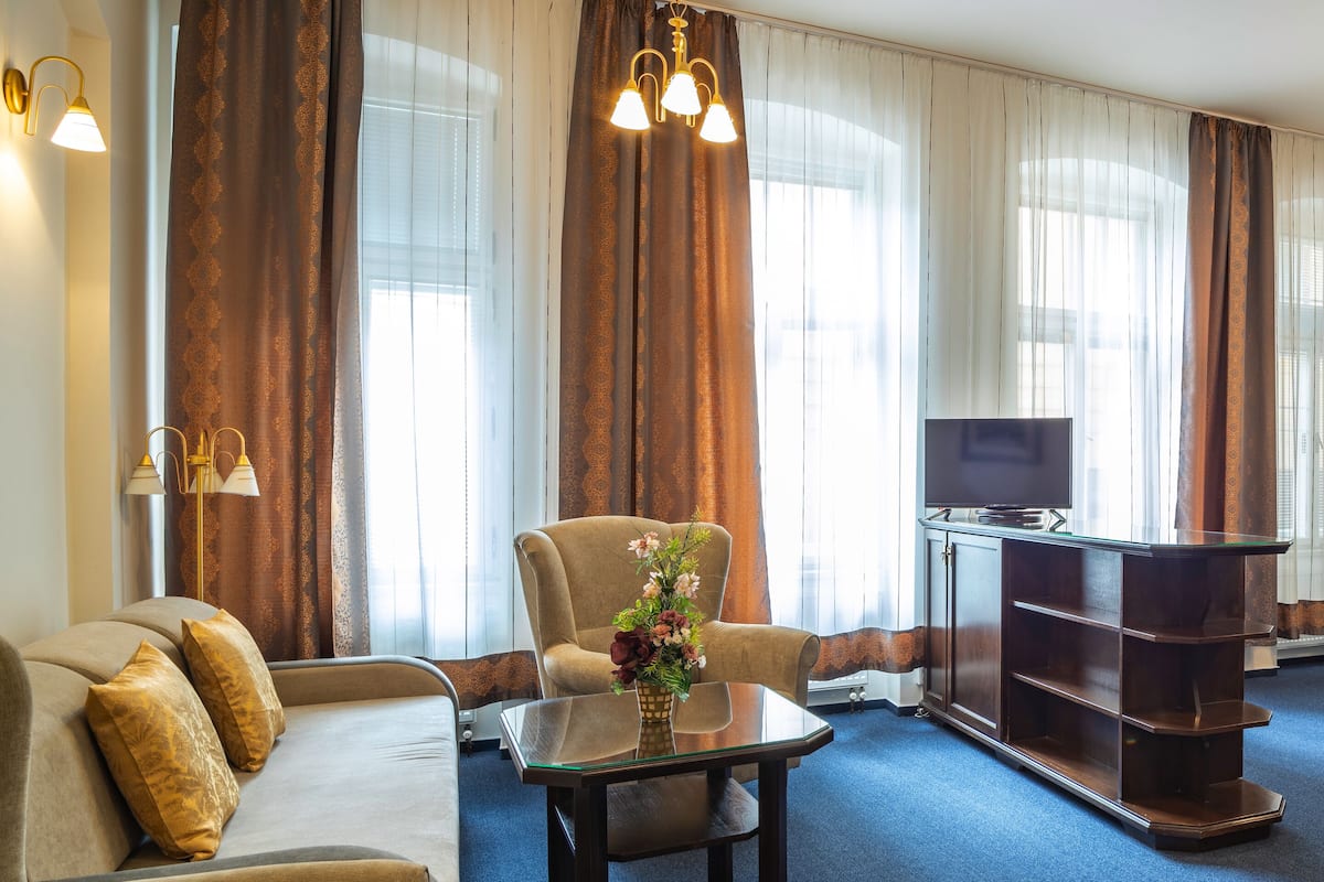 Una sala de estar con sofá, sillones, una mesa de centro, televisor y estantería.