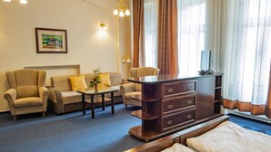 Et hotelværelse med en seng, to sofaer, et skrivebord og et fjernsyn.