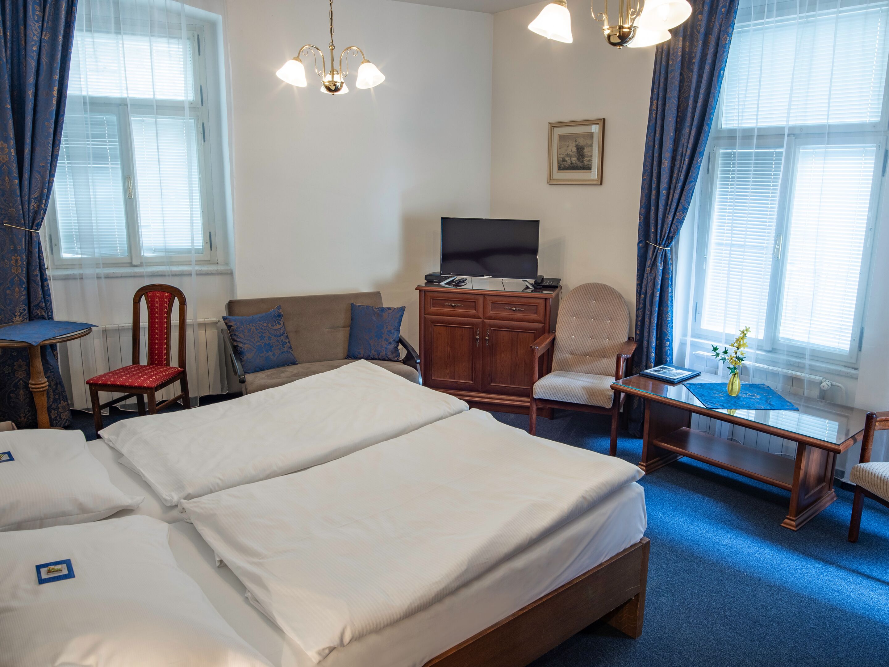 Une chambre d’hôtel avec un grand lit, un bureau, une chaise, une télévision et une fenêtre avec des rideaux.
