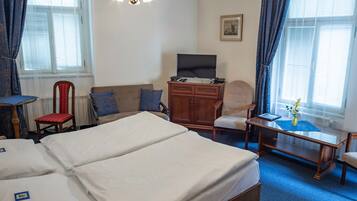 Une chambre d’hôtel avec un grand lit, un bureau, une chaise, une télévision et une fenêtre avec des rideaux.