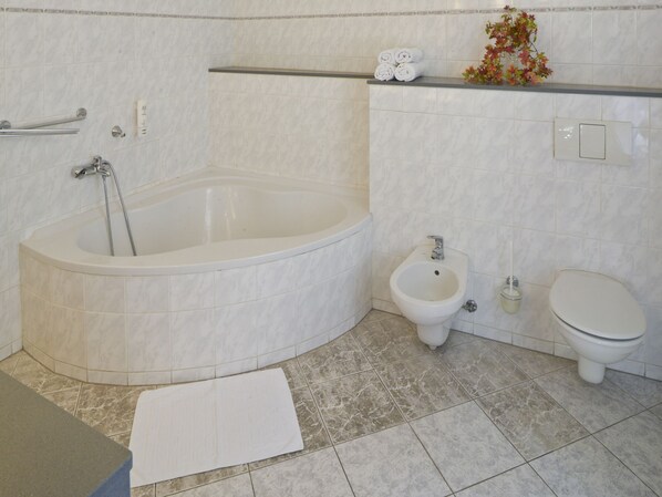 Une salle de bain équipée d’une baignoire, d’un bidet, de toilettes et d’un porte-serviettes.