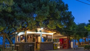 Ein Restaurant am Meer mit Außenbereich, überdachtem Sitzbereich und Blick auf das Meer.