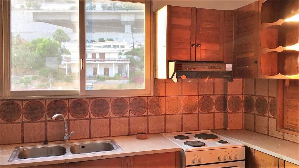 A kitchen with a window, a stove, and wooden cabinets.