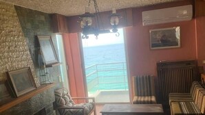 Ein Wohnzimmer mit Kamin, einer Couch, einem Tisch und Meerblick vom Balkon.