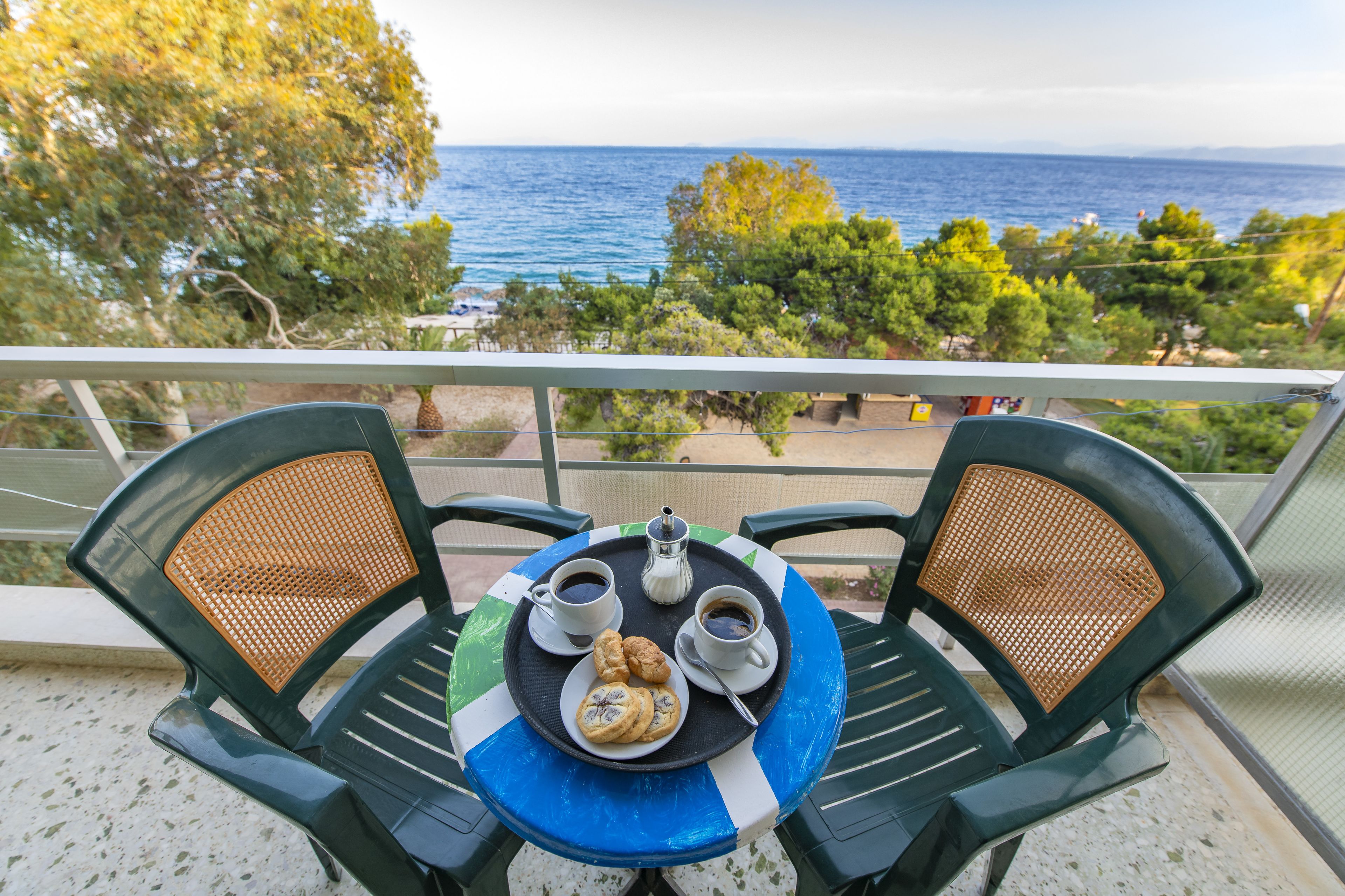 Una mesa con una bandeja de comida y bebidas, dos sillas y vistas al mar.