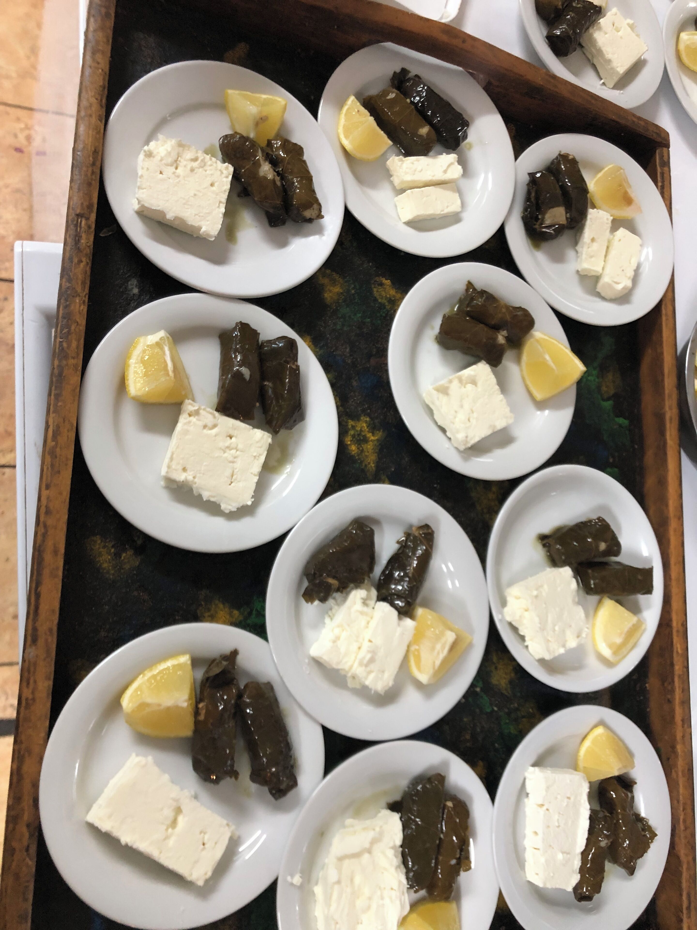 Una bandeja con platos de hojas de parra rellenas y queso feta, dispuesta sobre una mesa.