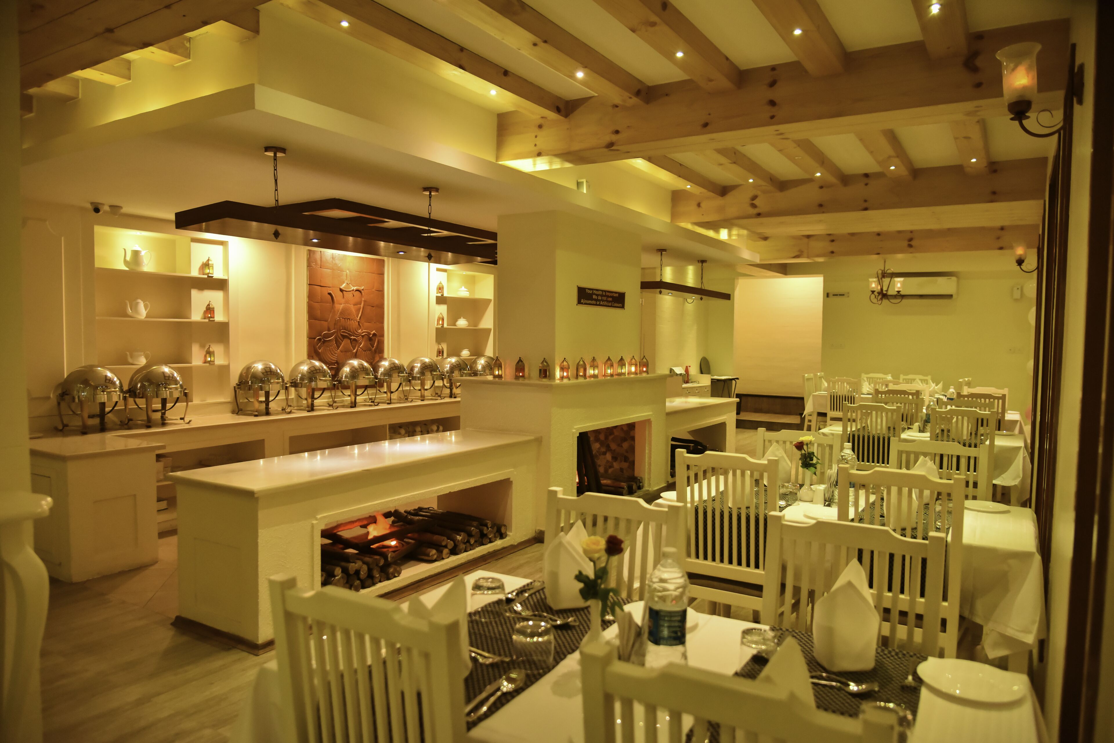 Un restaurante con mobiliario blanco, una isla central con botelleros y un techo de madera.