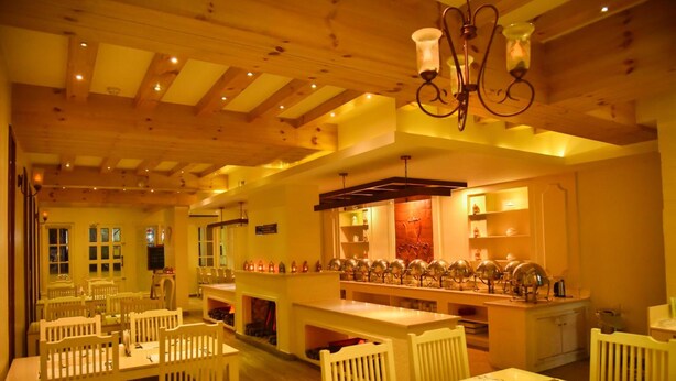 Un restaurante con vigas de madera, mesas y sillas blancas.