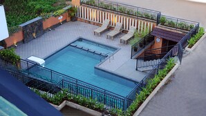 Zona de piscina en la azotea con piscina rectangular, sillas de descanso y un área de estar cubierta.