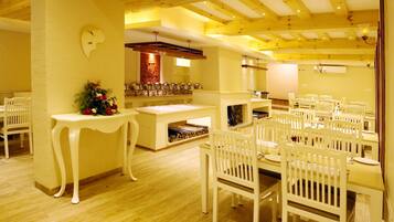 A dining area with white chairs and tables, a fireplace, and a fire exit sign.