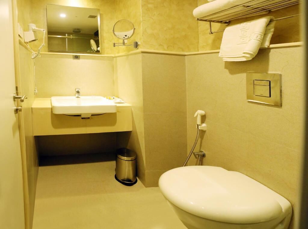 A bathroom with a sink, mirror, toilet, and towel rack.