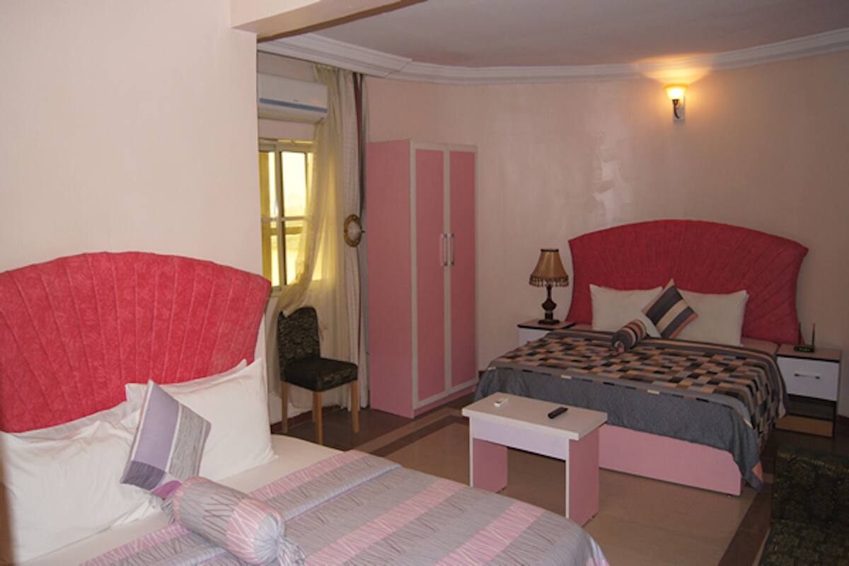 A bedroom with a bed, a chair, a desk, and a wardrobe.