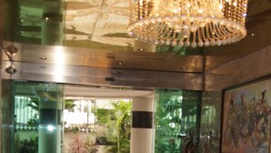 A lobby with a marble floor, a red leather sofa, a chandelier, and a painting on the wall. - Royalview Hotel And Suites (Lagos)