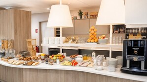 Un ricco buffet per la colazione con diverse pietanze, una macchina del caffè e una pianta.