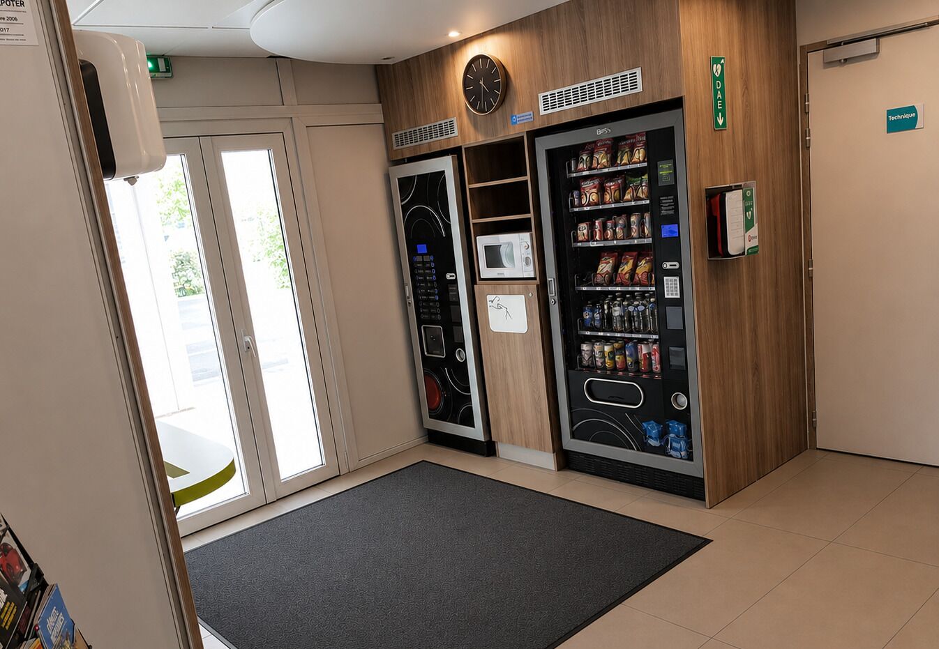 A clean, modern room with a microwave, a vending machine, and a clock on the wall.