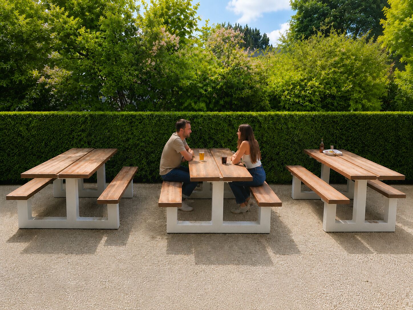 A picnic area with wooden benches and tables, surrounded by greenery.