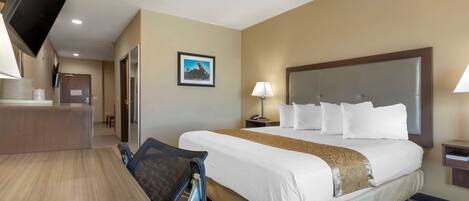A hotel room with a large bed, a desk, a chair, a TV, and a picture on the wall.
