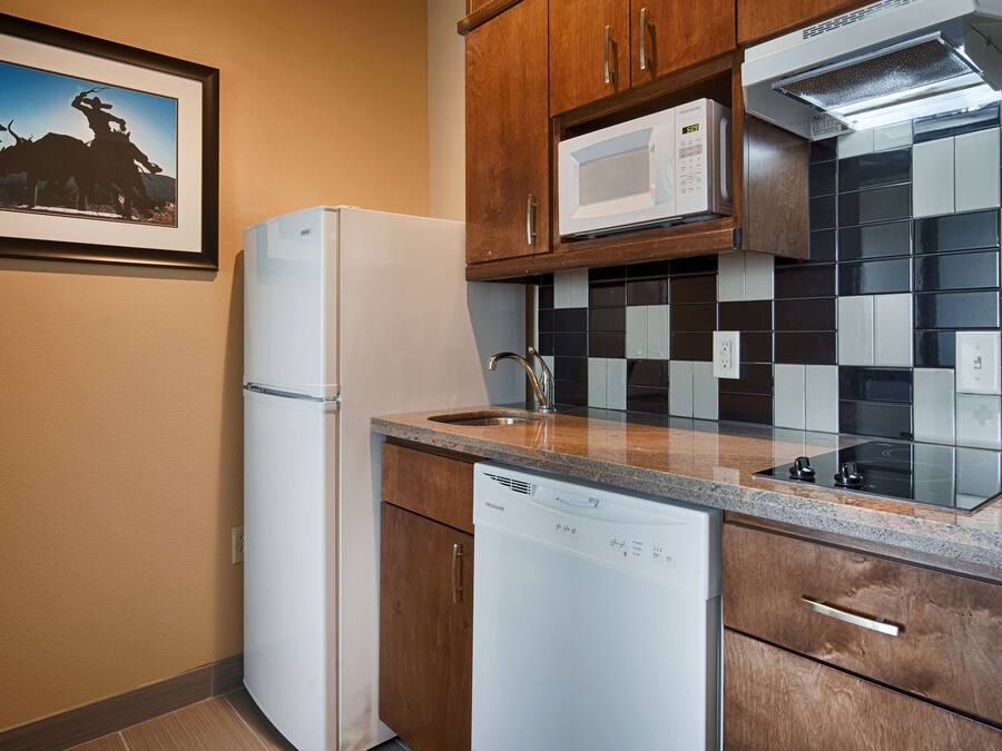Una cocina compacta equipada con refrigerador, microondas, lavavajillas y un salpicadero de azulejos.
