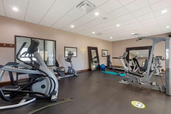 A gym with various exercise equipment including treadmills, stationary bikes, and weight machines.