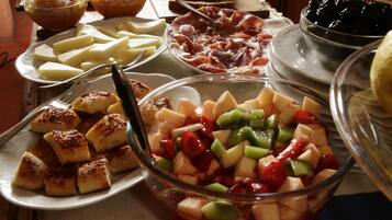 A table with various food items including bread, cheese, ham, and a fruit salad.