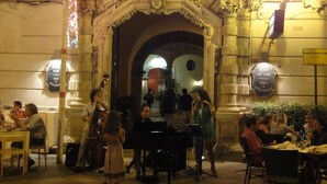Un espace extérieur aménagé pour les repas, avec des arches en pierre et un piano.
