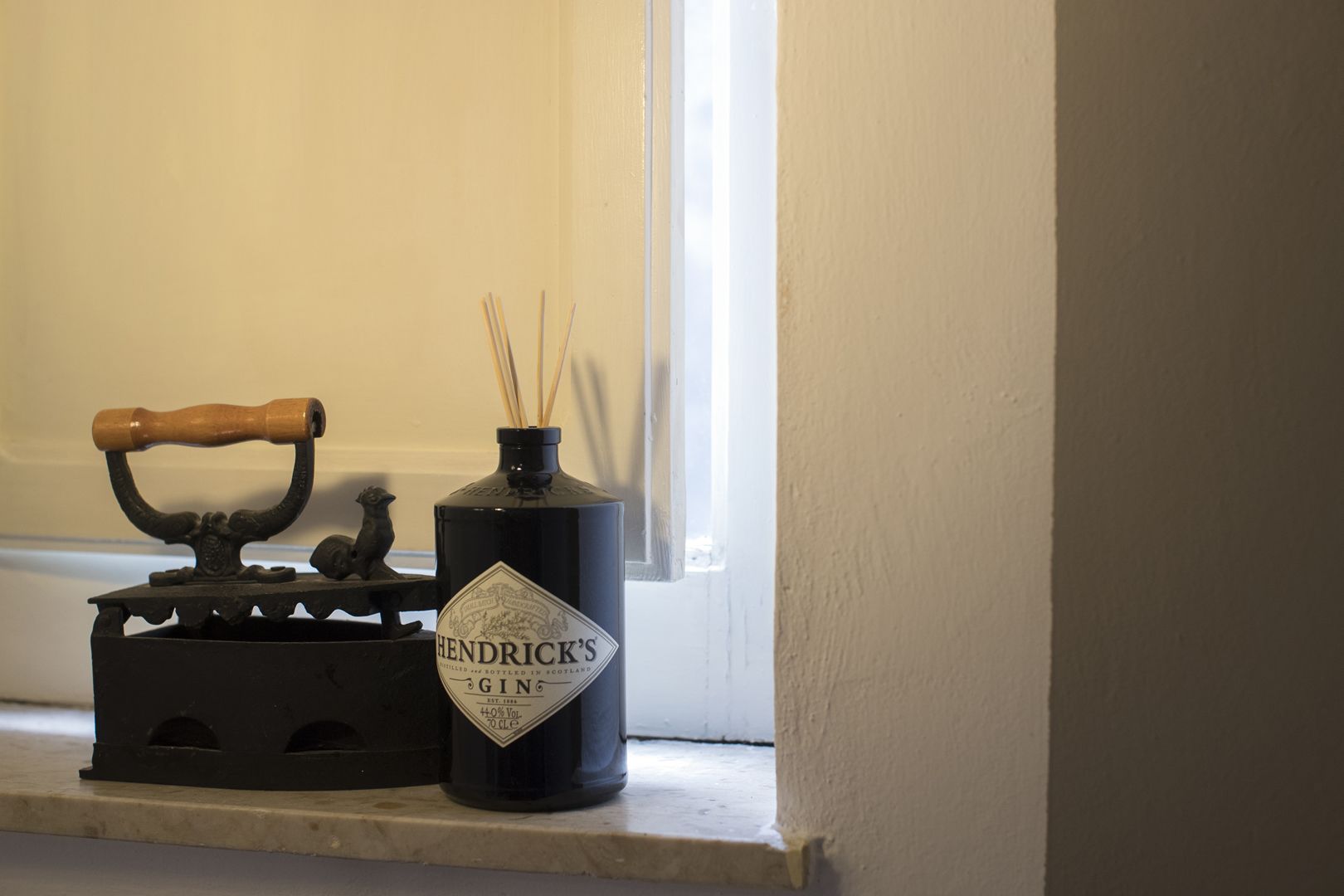 A shelf with a vintage iron and a bottle of Hendrick's Gin.