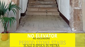 Un escalier en pierre mène à une pièce où une pancarte indique qu’il s’agit d’un établissement proposant à la fois hébergement et petit-déjeuner.