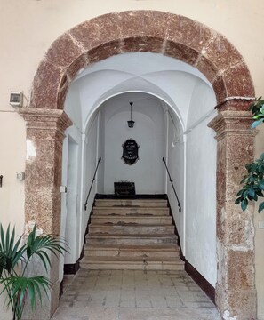 Un escalier en pierre mène à une pièce où une pancarte indique qu’il s’agit d’un établissement proposant à la fois hébergement et petit-déjeuner.