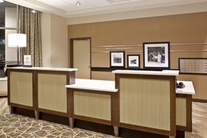 A hotel reception area with a reception desk, a framed welcome sign, and a wall with framed pictures. - Hampton Inn & Suites Minneapolis / Downtown (Minneapolis)