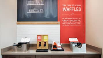 Een wafelstation met twee dispensers voor wafelbeslag en een bord waarop wafels worden aangeboden.