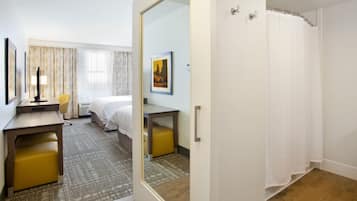 Een hotelkamer met een bed, een bureau, een stoel, een spiegel en een douche.