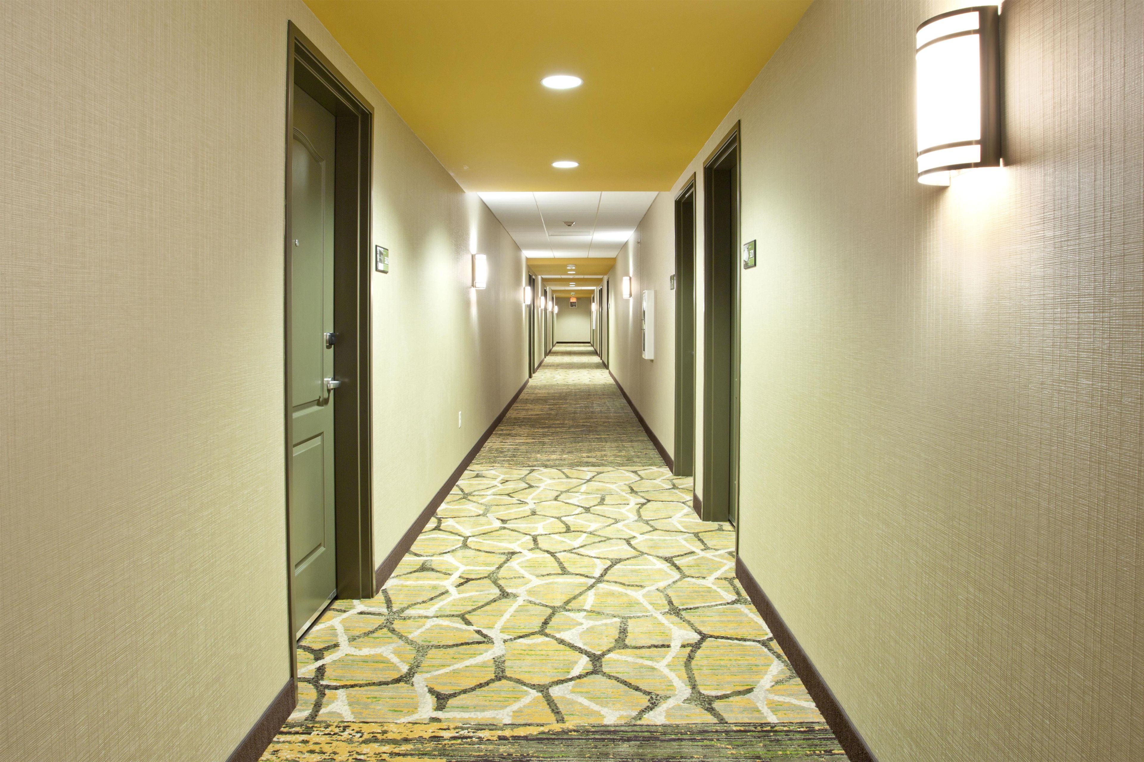 Ein Hotelkorridor mit Teppichböden, Türen und Wandleuchten.