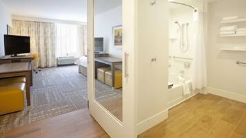 A hotel room with a shower, a TV, a desk, and a bed.