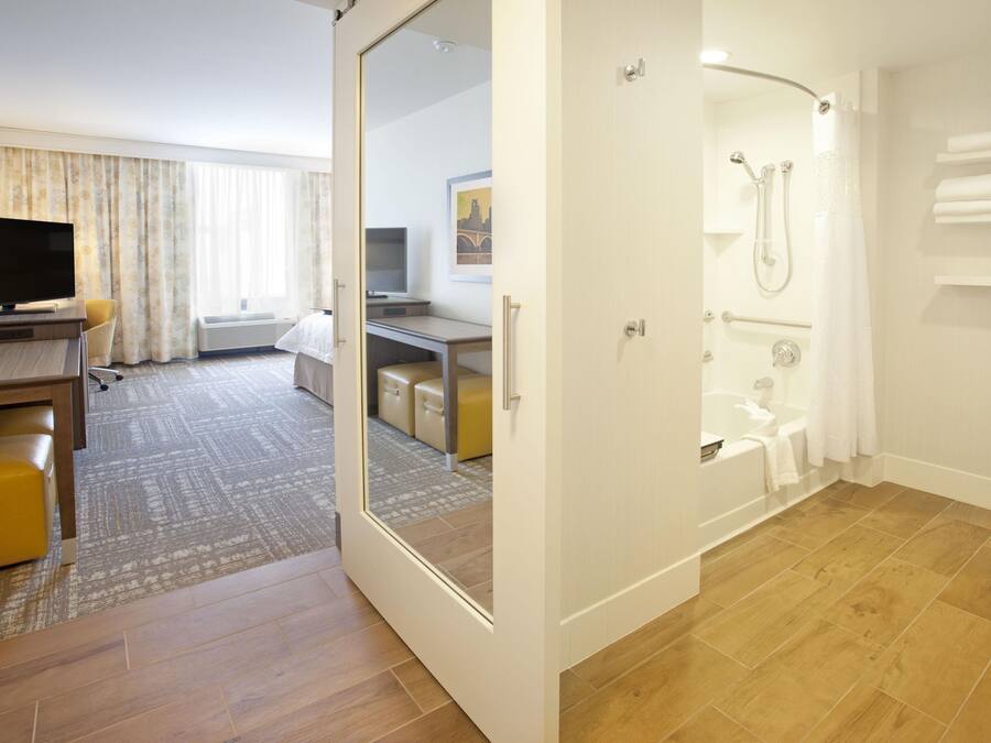 A hotel room with a shower, a TV, a desk, and a bed.