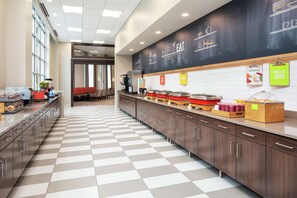 A modern kitchen area with a checkered floor, a chalkboard wall with menu items, and various food service stations. - Hampton Inn & Suites Minneapolis / Downtown (Minneapolis)