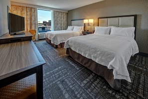 A hotel room with two beds, a desk, a television, and a view of the city. - Hampton Inn & Suites Minneapolis / Downtown (Minneapolis)