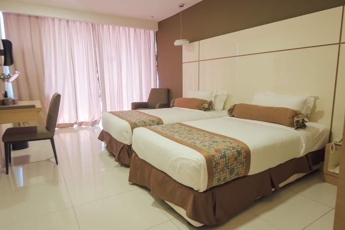 A hotel room with two beds, a desk, and a chair.