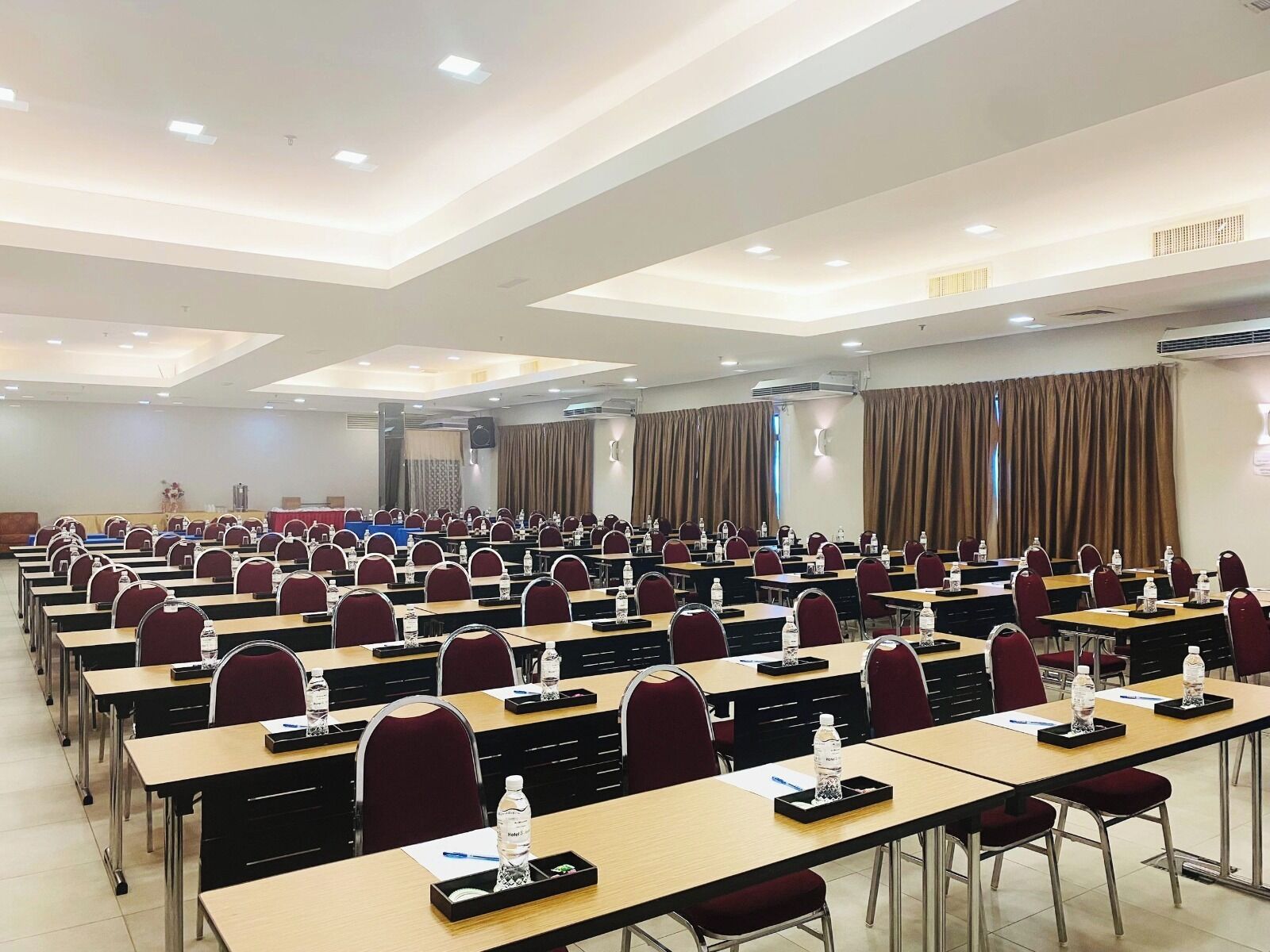 Un salón de conferencias con filas de mesas y sillas, equipado con tarjetas de identificación y botellas de agua.