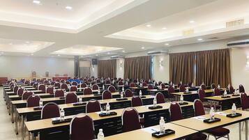 Un salón de conferencias con filas de mesas y sillas, equipado con tarjetas de identificación y botellas de agua.