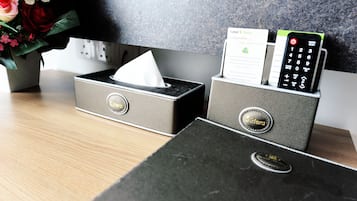 A hotel reception desk with a tissue box, a business card holder, and a remote control.